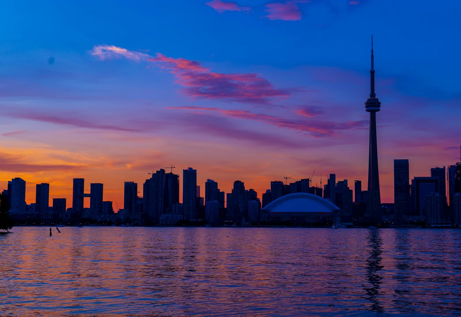 Toronto skyline and CN Tower at sunset, reflected on Lake Ontario